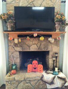 Stone fireplace decorated with flowers pumpkins, and quilts for Fall