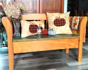 Wood bench decorated for fall with crocheted pumpkins and pillows with pumpkins on them