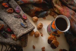 Fall scene with a sweater, coffee, throw, and nuts scattered around