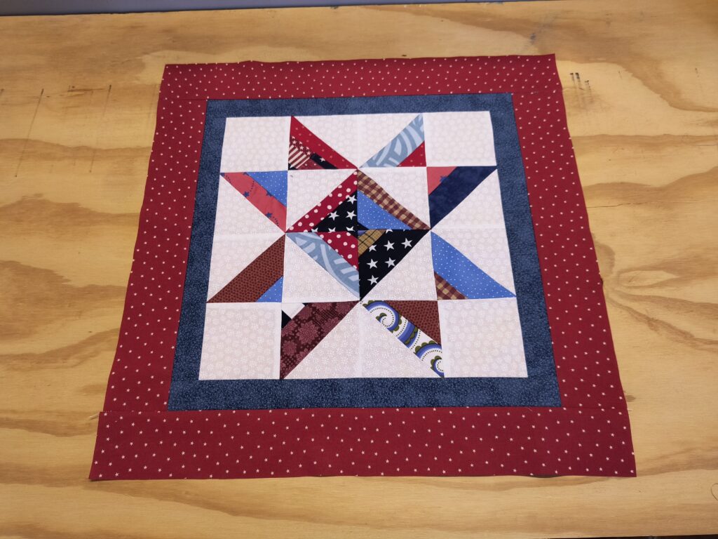 a star wall hanging using half square string blocks in red, white, and blue.